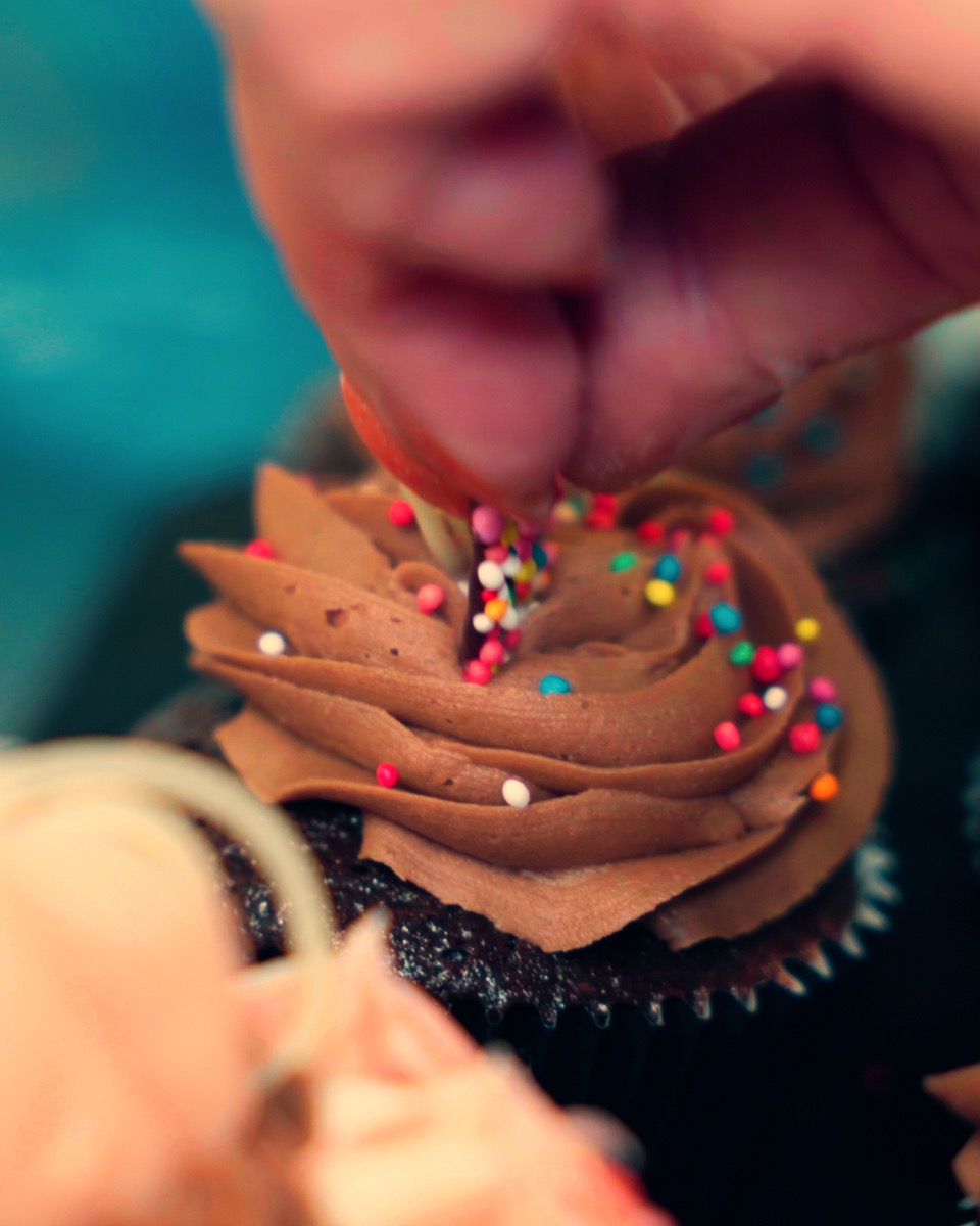 Decorating a cupcake with sprinkles